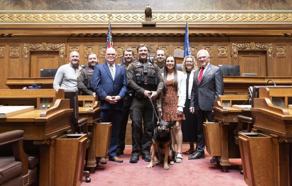 A large group with a dog and an award