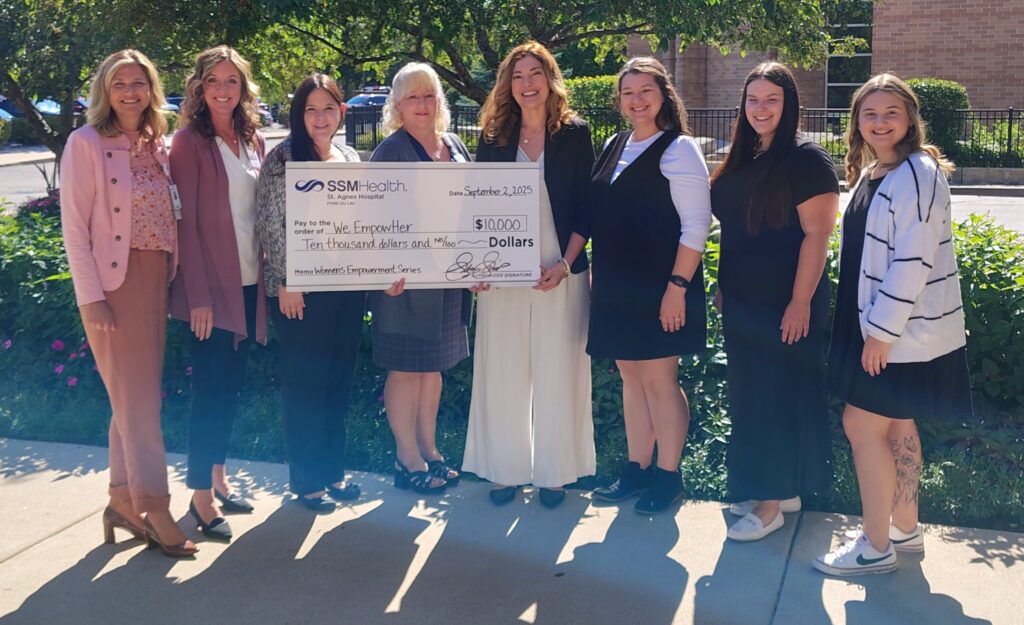 A group of eight women and a big check outside