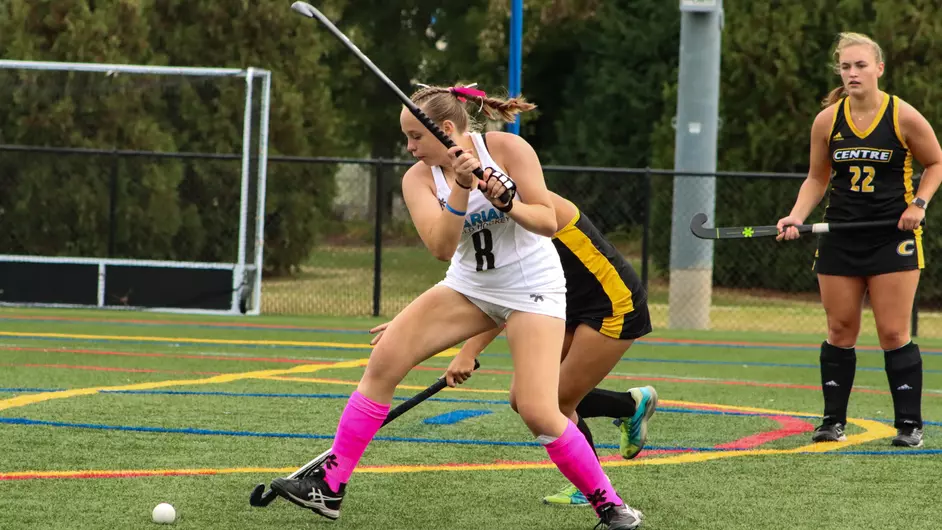 Women playing college field hockey