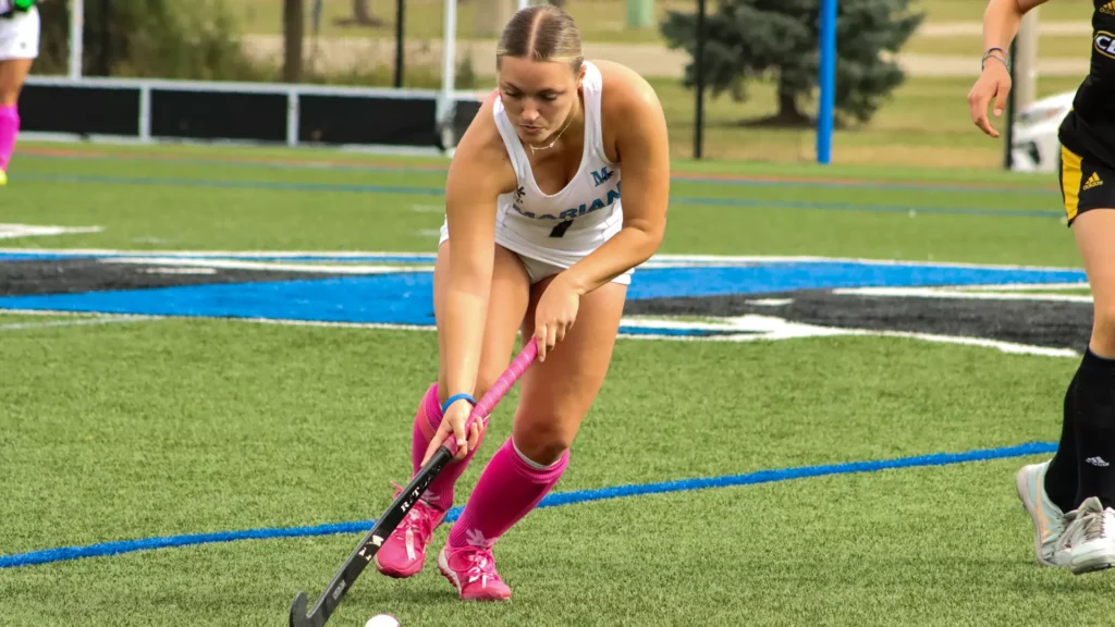 Women playing college field hockey