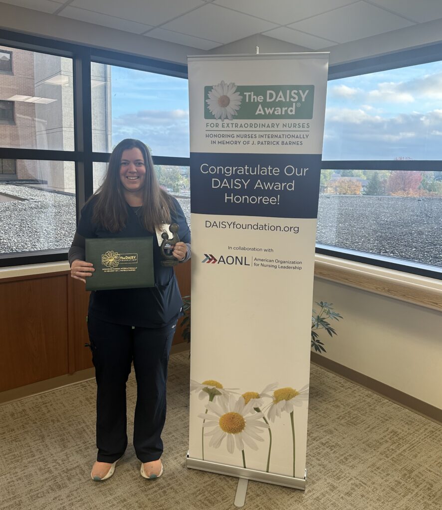 A woman standing by a sign holding a certificate