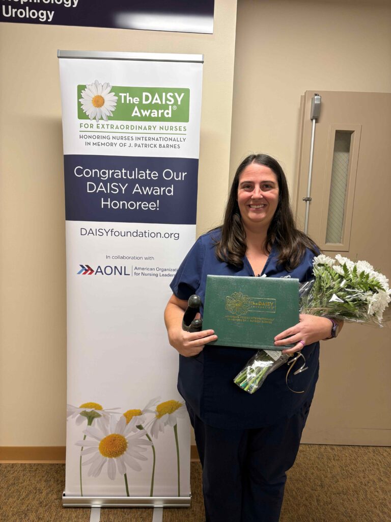A nurse holding a certificate and some flowers