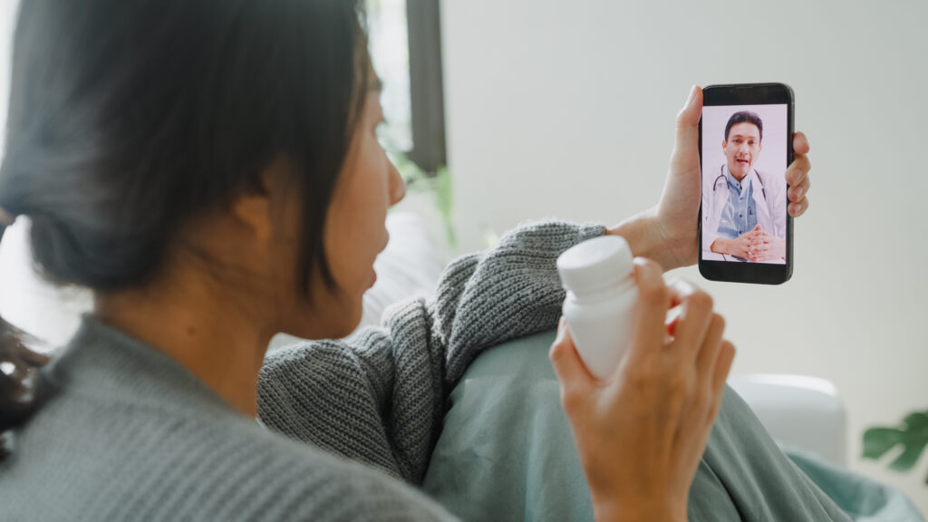 A woman holding a bottle talking to her doctor on a cellphone