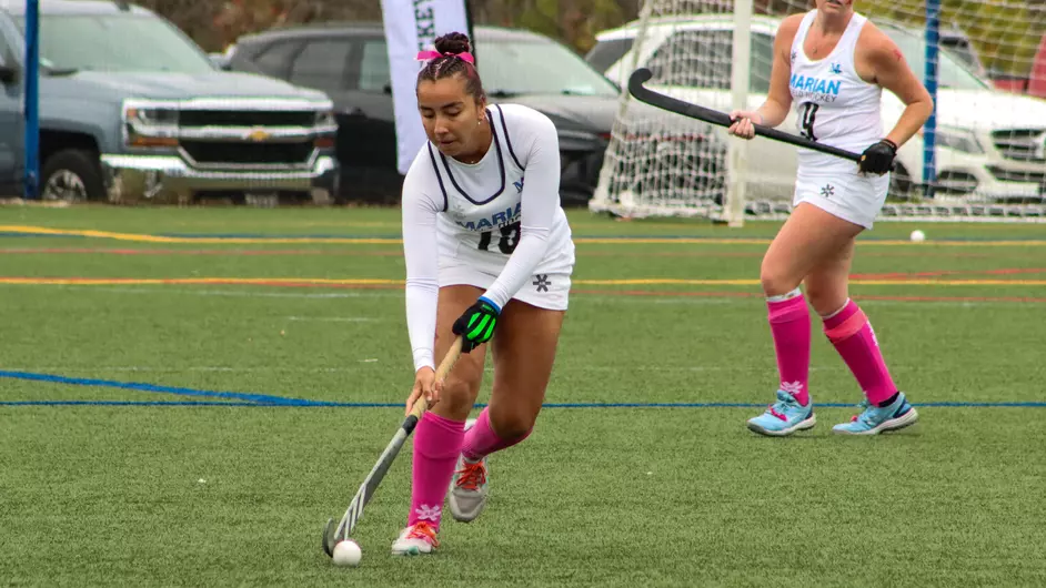 Women playing college field hockey
