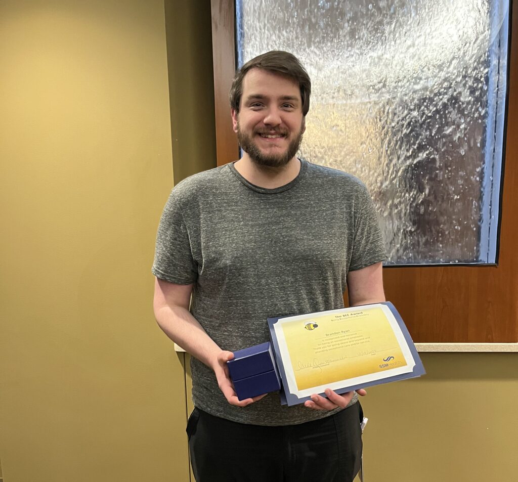 A smiling man holding an award and a box