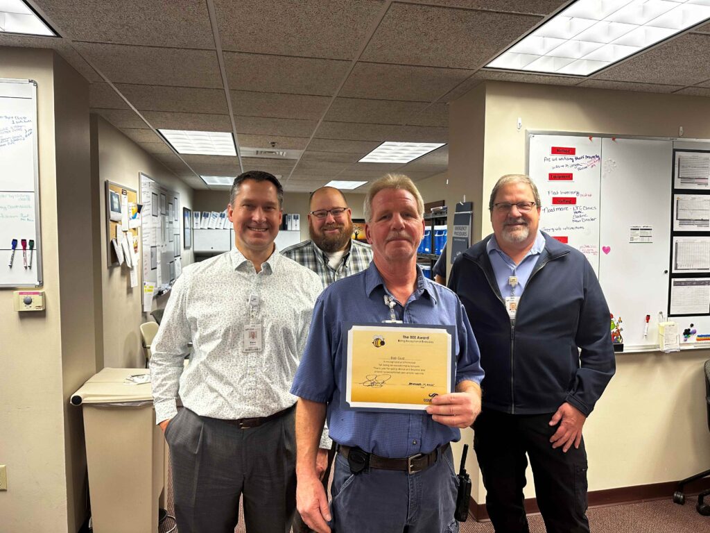 Three men with one holding an award