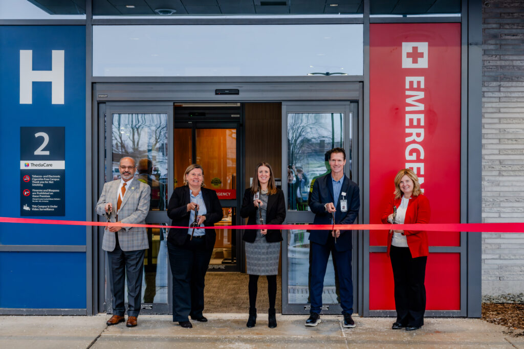 Five people standing outside for a ribbon cutting