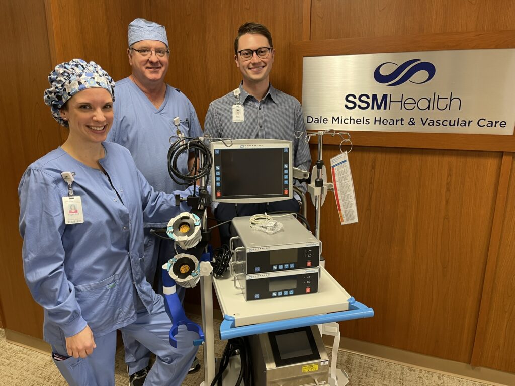 Three medical people with a piece of equipment