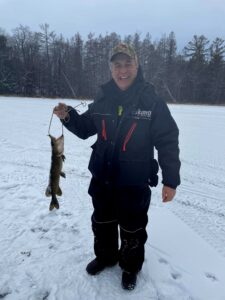 A man holding a fish out on the ice