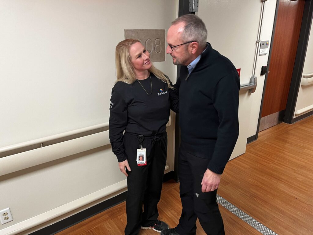 An elderly man and a female nurse standing in a hall
