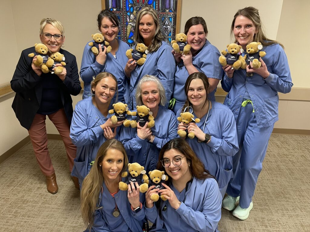 A large group of nurses holding little stuffed bears