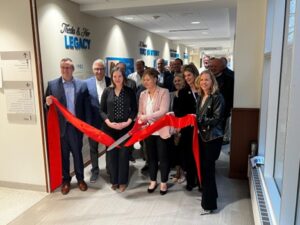 A group doing a ribbon cutting in a hallway