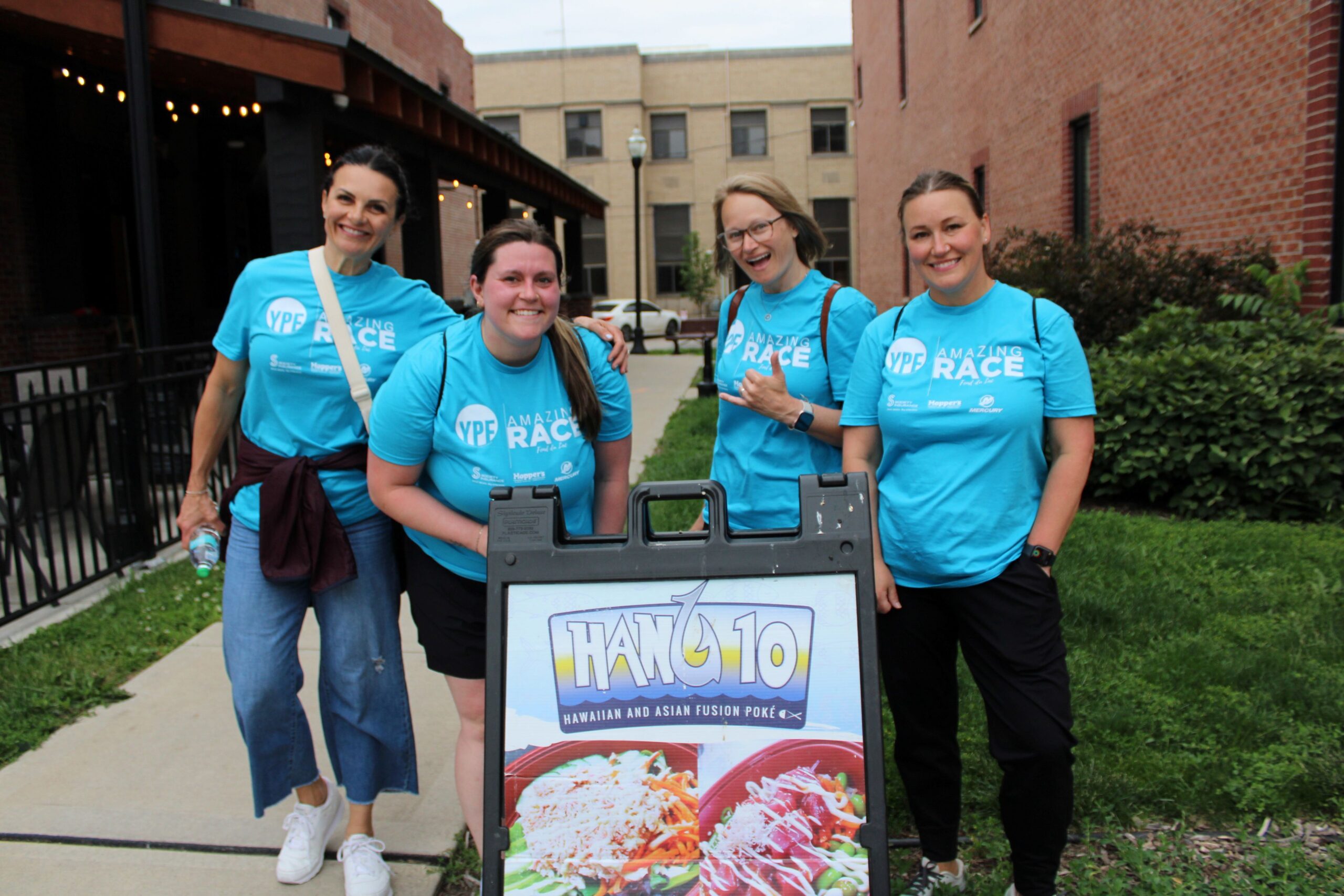 Four women outside by a sign