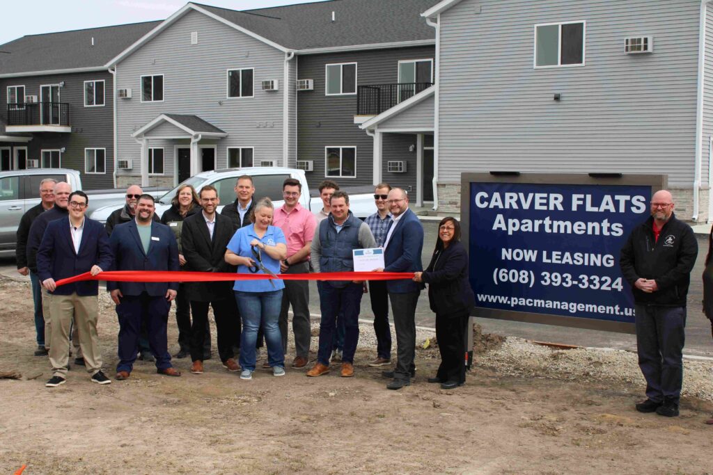 A large group of people outside of an apartment building for a ribbon cutting