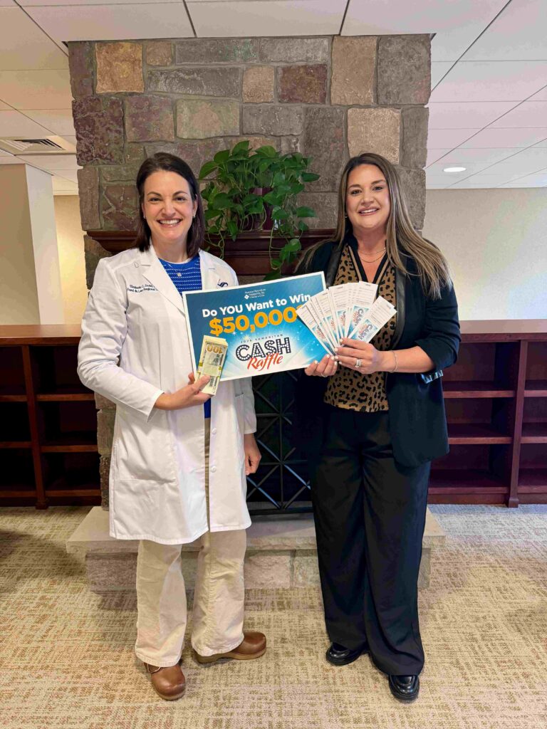 Two women holding a sign and raffle tickets