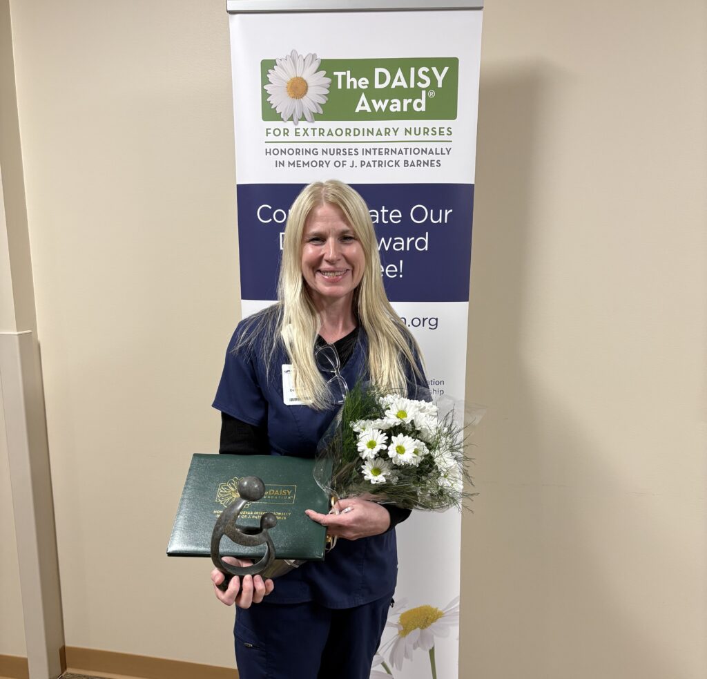 A female nurse holding an award and flowers