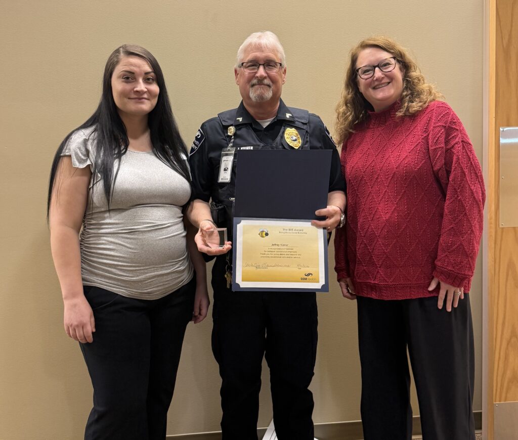 Two women and a man holding an award