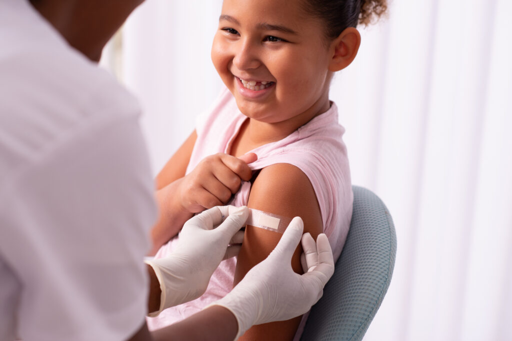 A female child getting a bandage on her arm