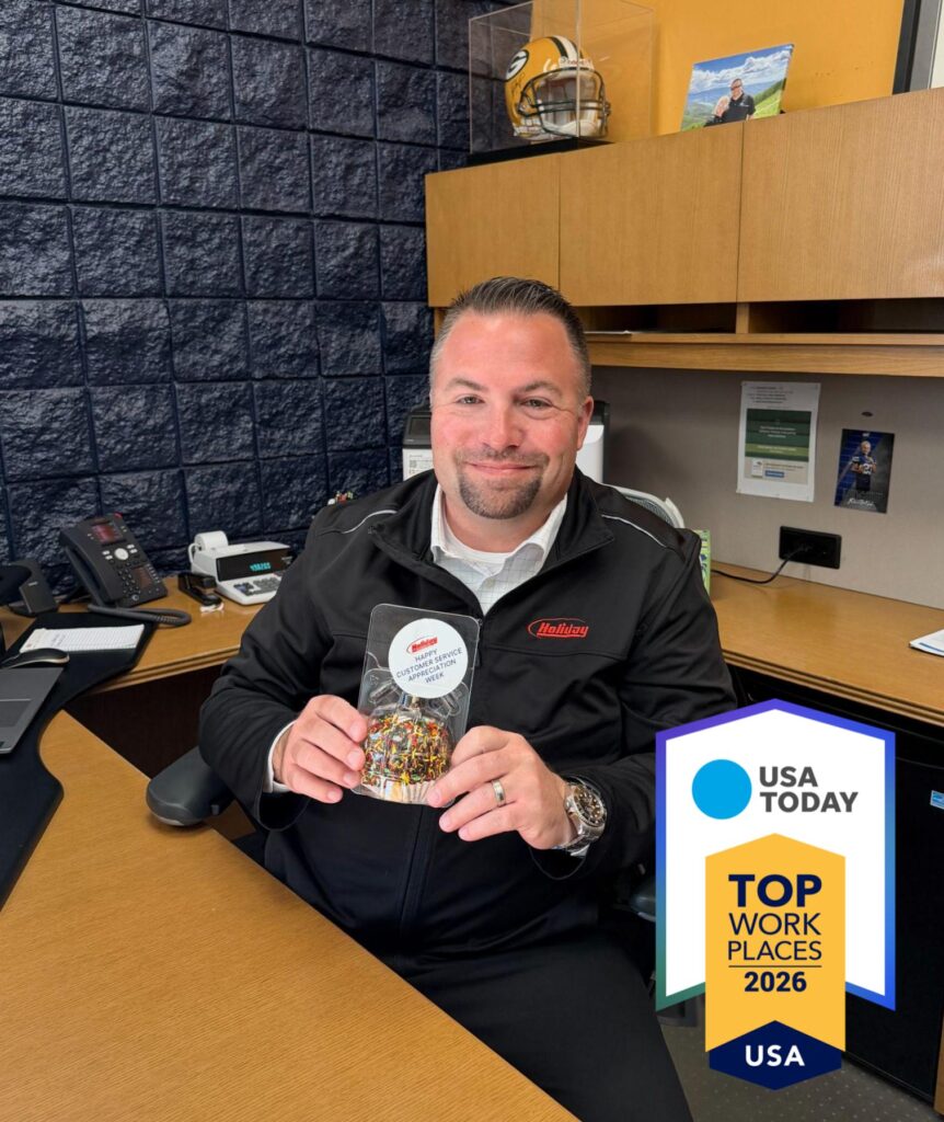 A middle aged man holding an award while sitting at a desk