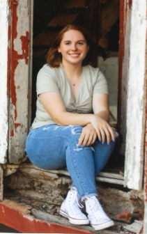 A smiling young woman sitting in a barn door