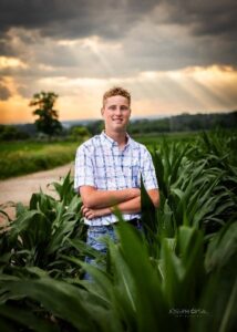 A smiling young man in a corn field