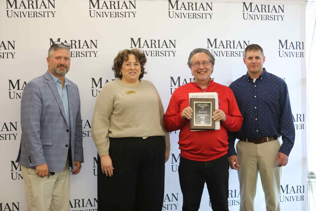 Four people with one holding an award