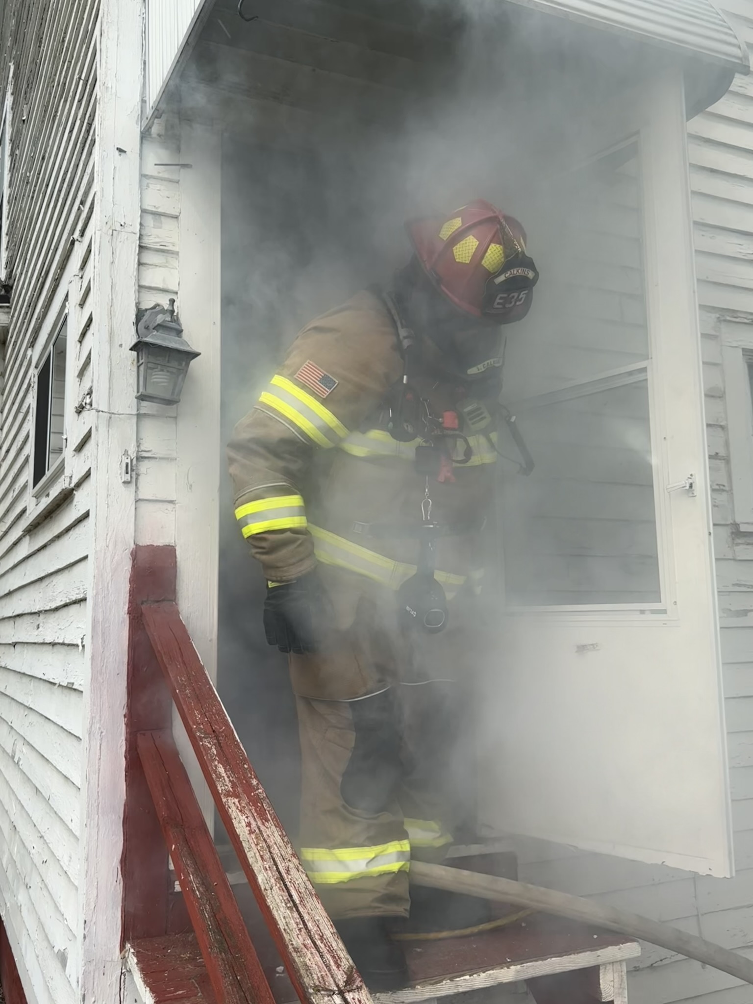 A firefighter coming out of a house