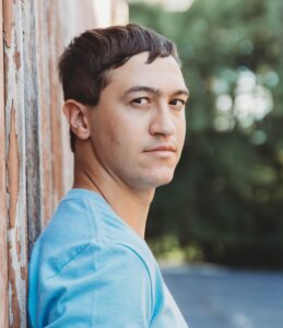 A young man leaning against a wall