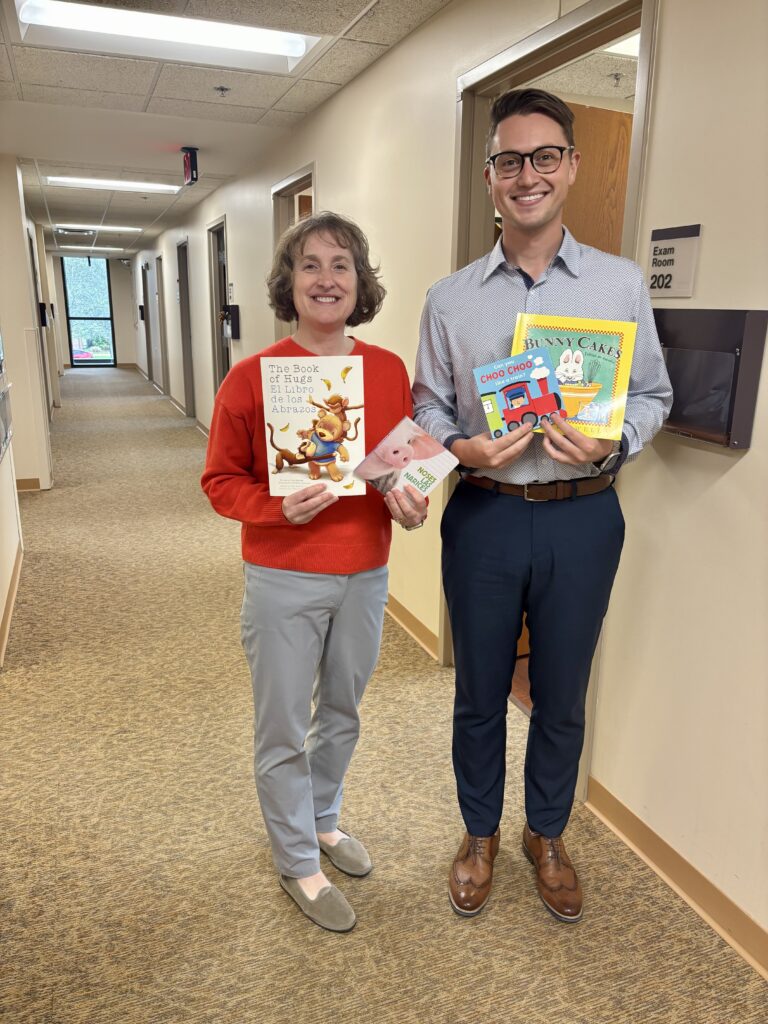 A woman and man standing in a hallway holding children's books