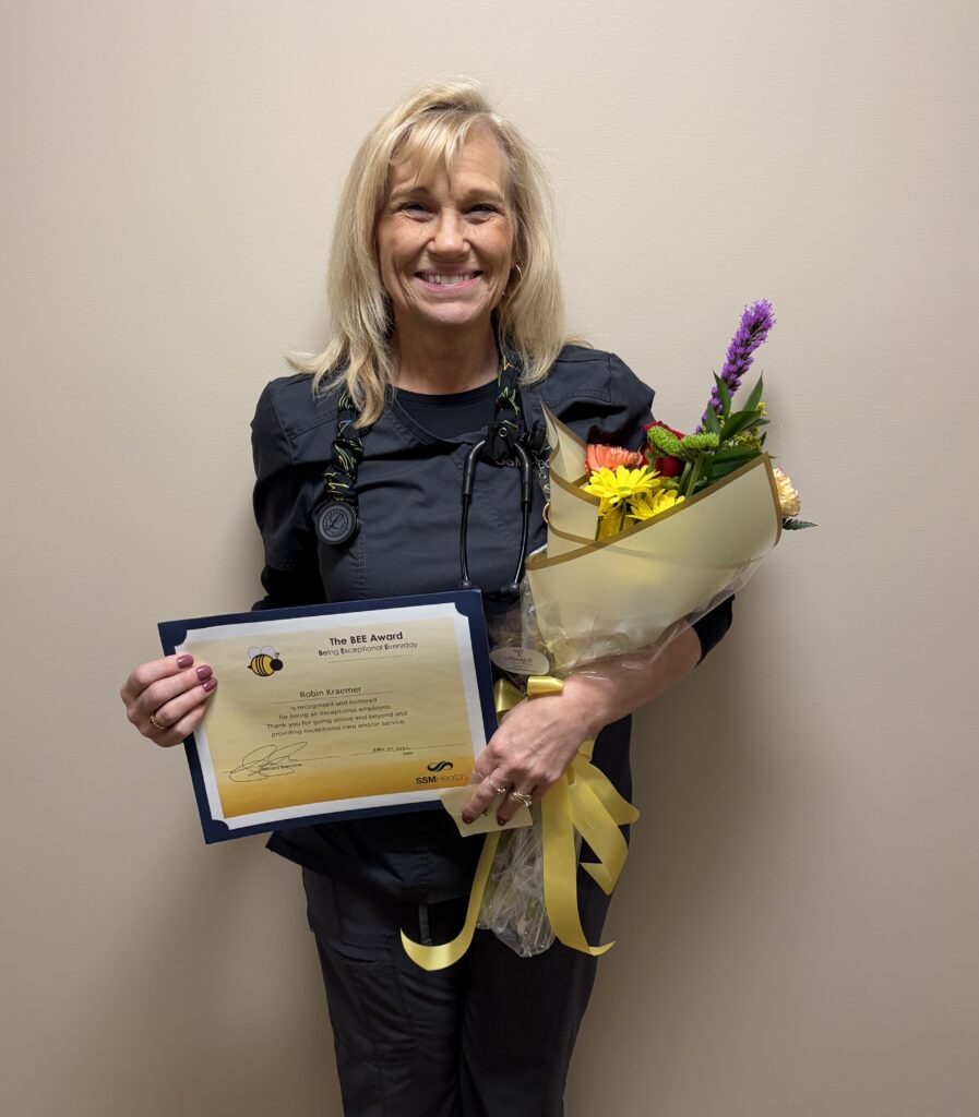 A smiling woman holding flowers and a certificate
