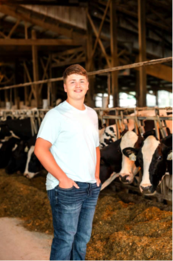 A smiling your man in a cow barn