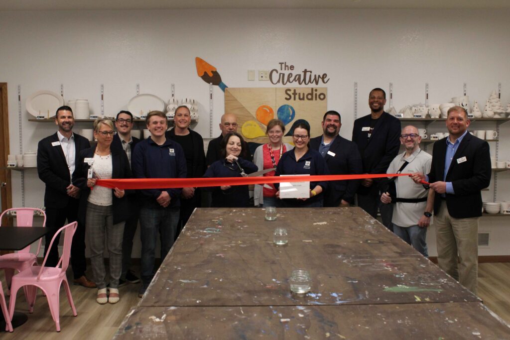 A large group inside by a table for a ribbon cutting