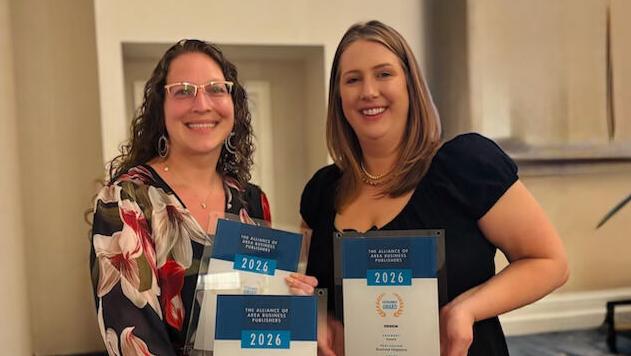 Two smiling women holding awards