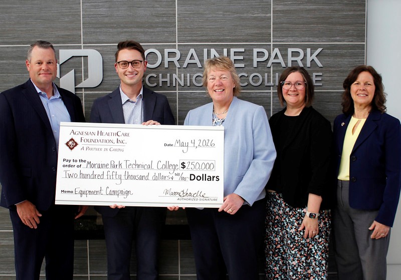 A group of five people holding a big check