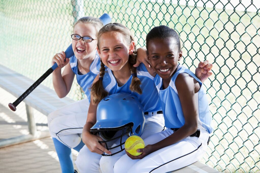 Three children playing baseball sitting on a bench