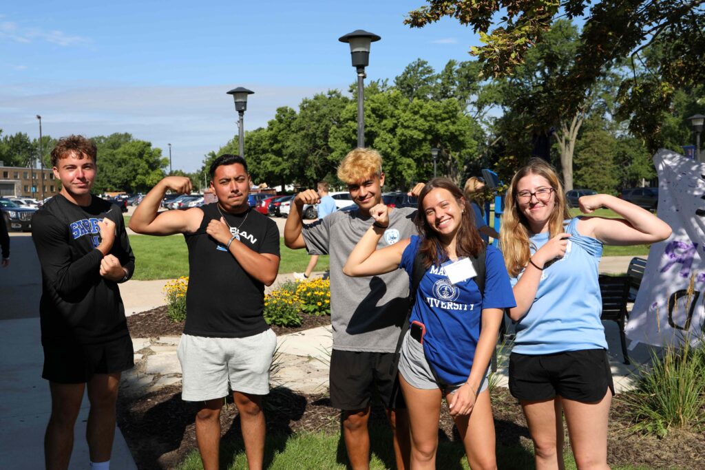 A group of five college students outside posing