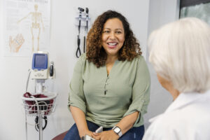 A women in an exam room talking to a doctor