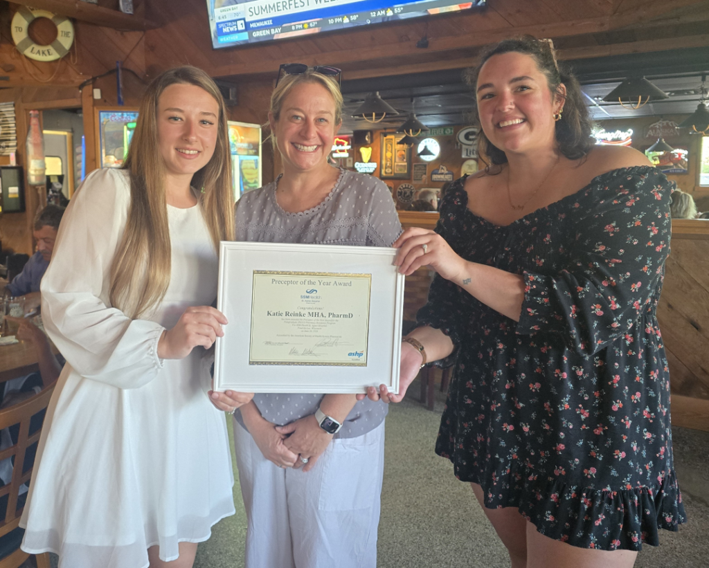 Three woman with one getting a certificate