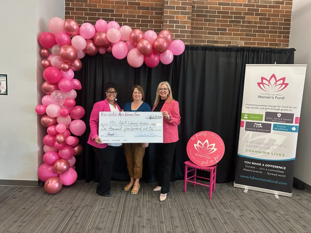 Three people with a big check and pink balloons