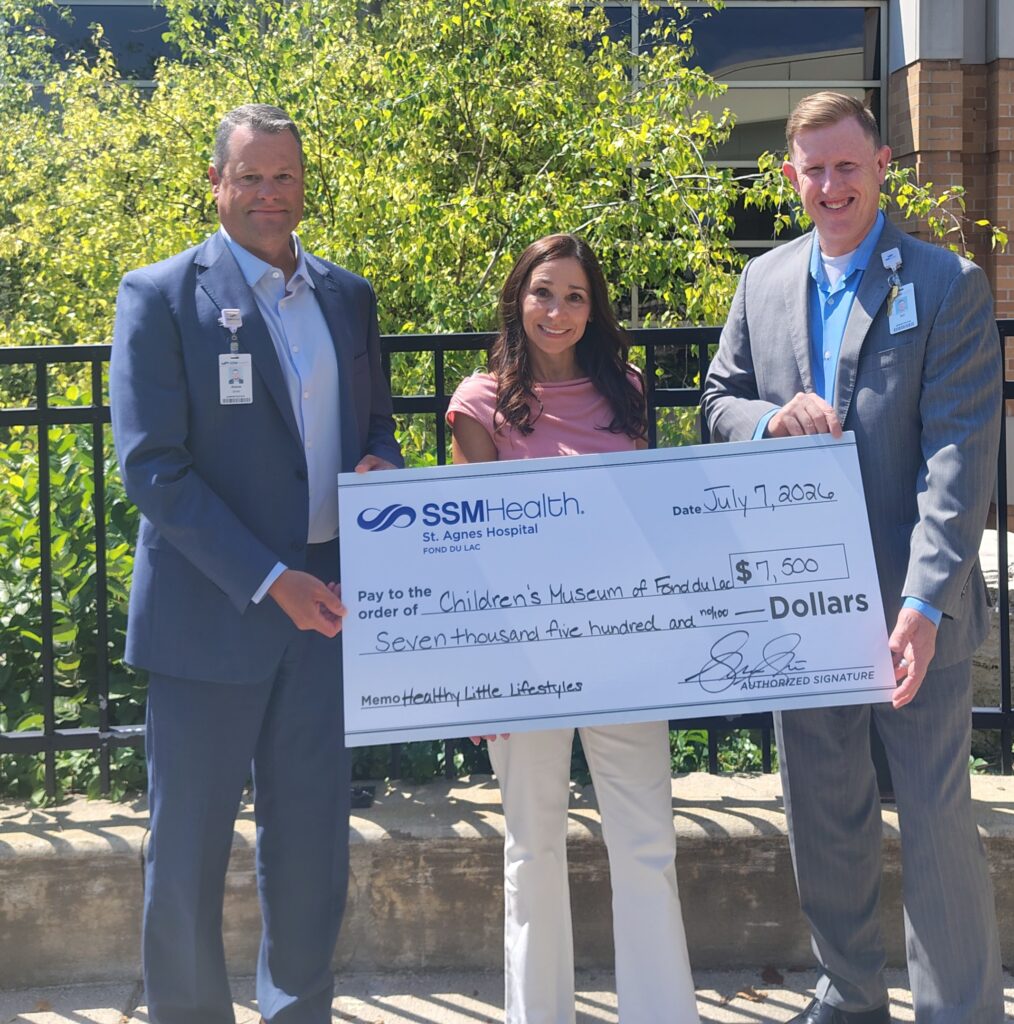 Three people outside with a big check