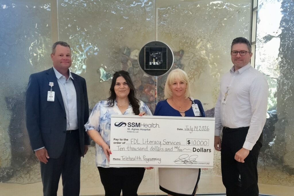 Four people standing with a big check