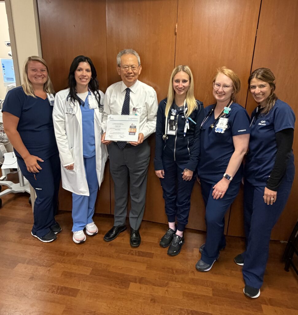 A group of people in a hospital with an award