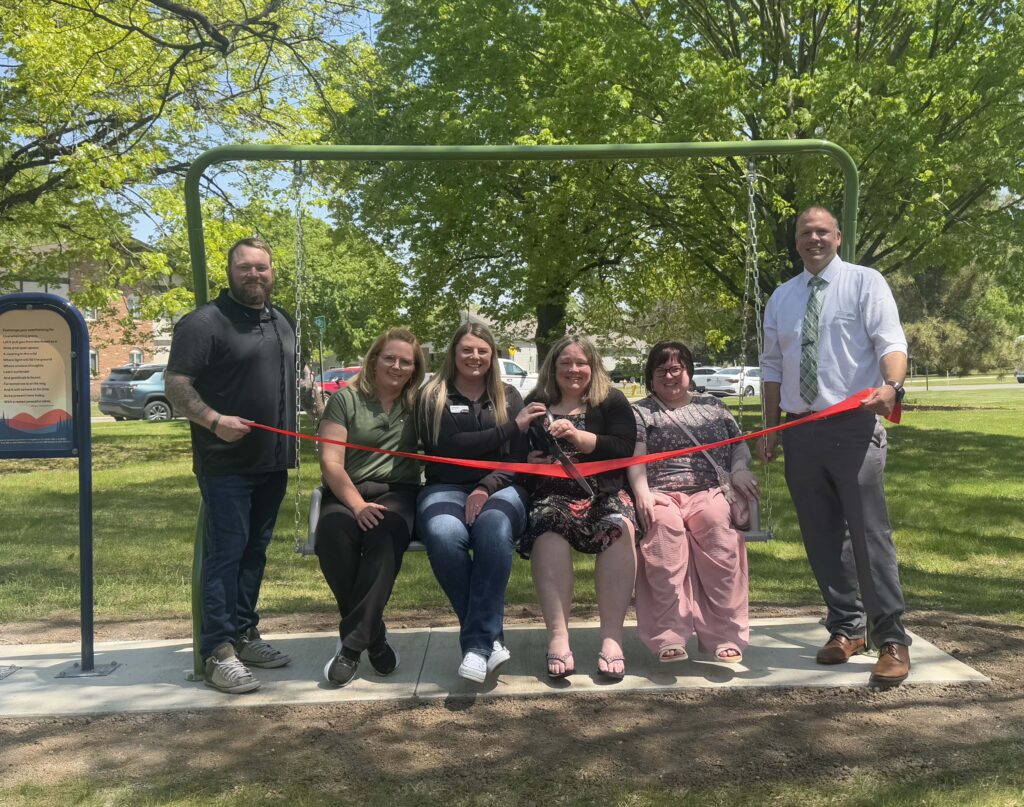A group of six people on a swing for a ribbon cutting