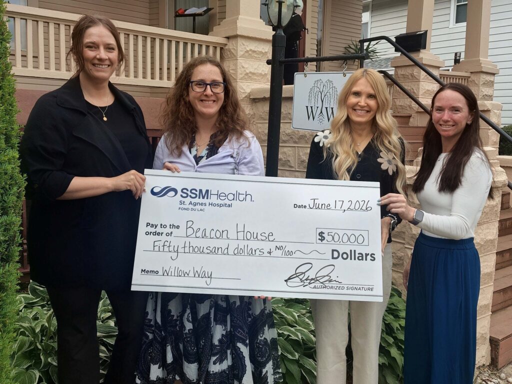 Four women outside with a big check