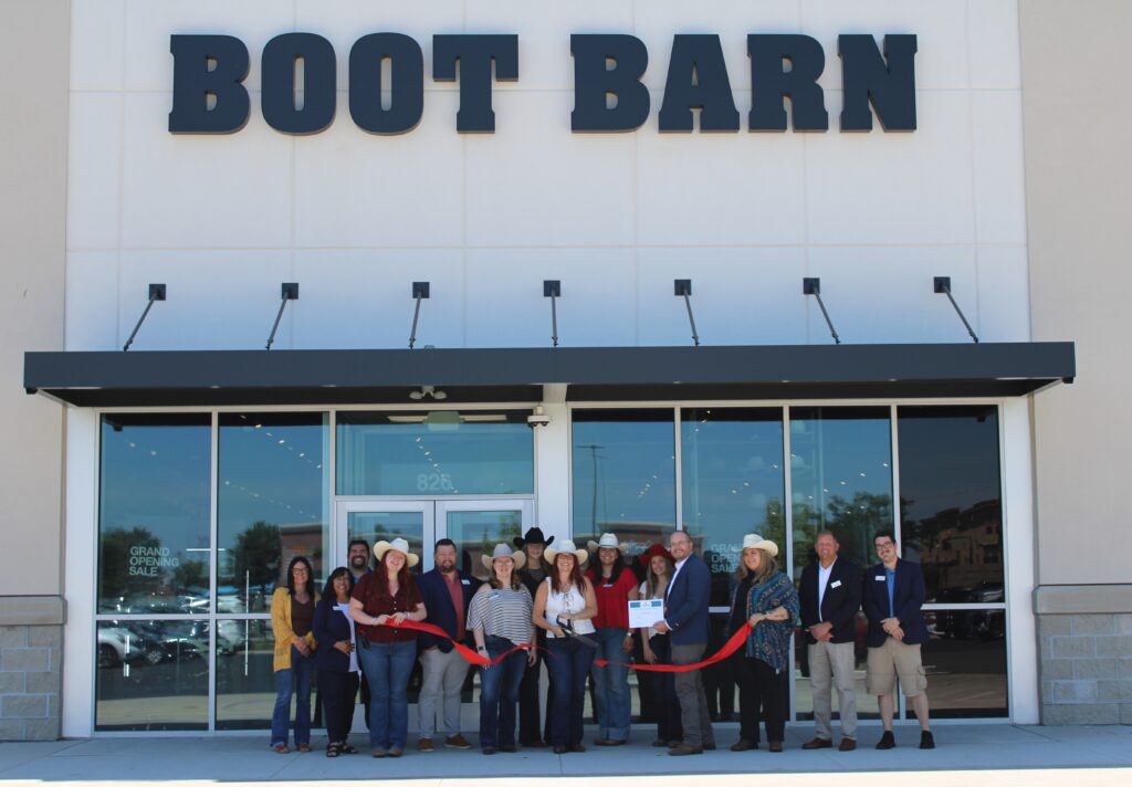 A group of people outside a store for a ribbon cutting