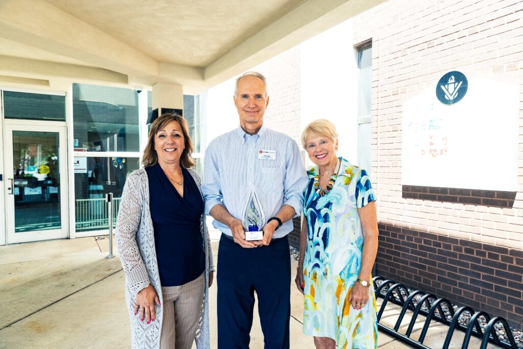 Two women and a man with an award