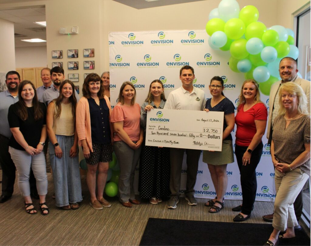 A large group inside with a big check