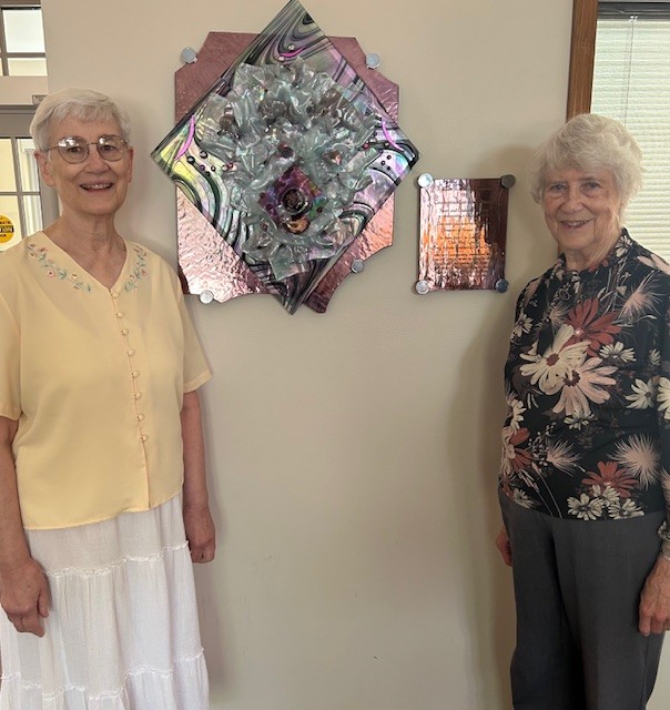 Two older women by a piece of art