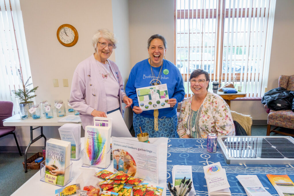 Three older women by a table display