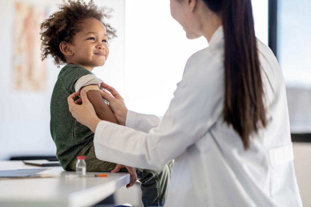 A small child getting a bandage put on their arm by a doctor